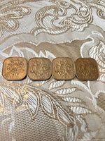 Four scalloped square Bahamas 15-cent coins laid in a row