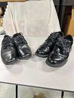 Both pairs of black dress shoes side by side on table