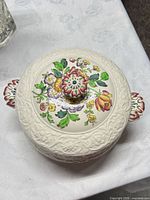 Lidded serving bowl top view showing floral design and embossed border