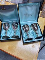 Two open presentation boxes showing four silver-plated goblets