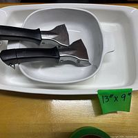 Large white rectangular baker with smaller handled pan nested inside and two detachable black handles