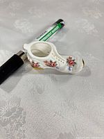 Side view of bone china shoe showing floral decals and gold sole