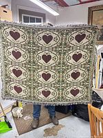 Full view of fringed woven throw displaying entire heart and floral pattern