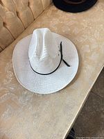 Full view of white straw cowboy hat on sofa