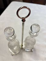 assembled cruet set showing two bottles with stoppers in metal stand