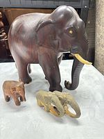 Large dark wood elephant, small dark wood elephant, two tan ring elephants grouped
