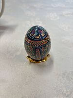 Front view of hand-painted ceramic egg on gold stand
