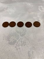 Five Canadian 1 cent coins laid out, showing reverse maple leaf design
