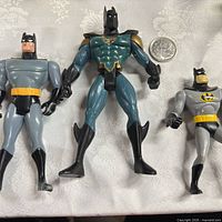 Three Batman action figures side by side on tablecloth