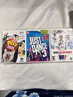 Front view of three Wii game cases: Petz Crazy Monkeyz, Just Dance 3, NHL Slapshot