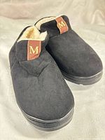 top view of slippers showing black suede-style uppers and M logo tab
