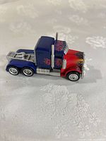 Side view of Optimus Prime semi-truck toy showing color scheme, exhaust stacks and wheels