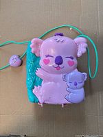 Front view of closed koala-shaped compact with teal cord
