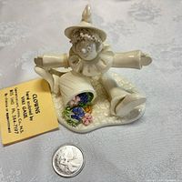 Full view of porcelain clown figurine with floral details and coin for scale