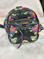 Front view showing embroidery, two zip compartments, tassel pull