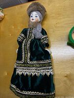 Front view of porcelain doll in green velvet Russian costume
