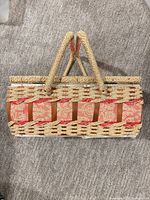 Closed wicker sewing basket showing ribbon accents and handles