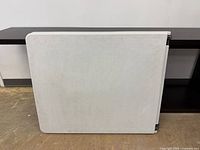 Table folded upright showing exterior white surface