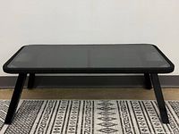 Full front view of coffee table showing glass top, metal legs and corded edge