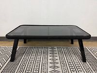 Full frontal view showing glass top, cord wrap, legs, rug for scale