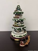 Full view of animated Christmas tree showing star topper, train, Santa sleigh, base