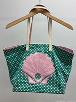 Front view showing green polka dot pattern, pink shell applique, and straps