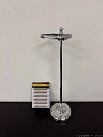 Full view of freestanding chrome toilet paper holder beside packaged handles