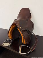 Left profile of saddle showing flap, stirrup iron, and leather