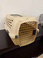 Front angled view of beige Kennel Cab crate showing ventilation holes and wire door