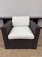 Front view of brown resin wicker lounge chair with cream cushions