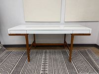 Front view showing full desk, white top, wood legs