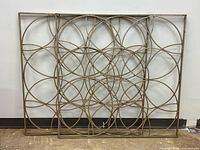 Both gold metal lattice wall panels leaning against wall