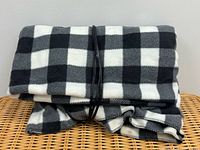 Folded black and white plaid fleece blanket with cord tied around