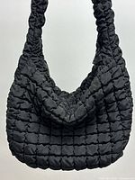 Front view of black quilted nylon tote showing slouchy shape
