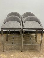 Four grey upholstered counter stools stacked front view