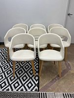 Front view of all eight cream faux leather dining chairs