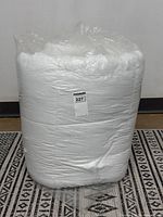 Rolled white duvet in plastic wrap