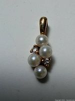 Front view of pendant showing four pearls and diamond accents