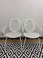 Front view of both white perforated metal chairs side by side