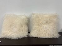 Front view of both white lamb wool pillows on surface