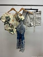 Three garments on rack: floral blouse, blue paisley romper, grey pinstripe shorts