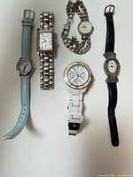 Five wristwatches displayed side by side showing overall lot contents