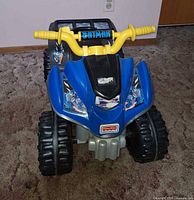 Front view showing blue body, Batman decals, yellow handlebars, Fisher-Price logo