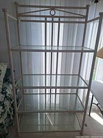 Front view of entire metal shelf unit showing frame and four glass shelves