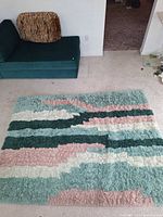 Full view of rug placed on carpet, showing colour pattern and overall shape