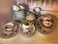 Full set displayed on countertop showing plates, bowls, cups, platter, creamer and sugar bowl