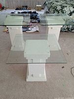 three glass-top pedestal tables, two tall one short