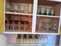 Cabinet with multiple sets of glasses on shelves and hanging below