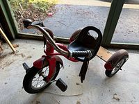 Full view of red Schwinn tricycle showing frame, seat, wheels, and handlebar
