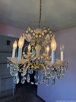 Full view of chandelier showing six lights, brass frame, crystals
